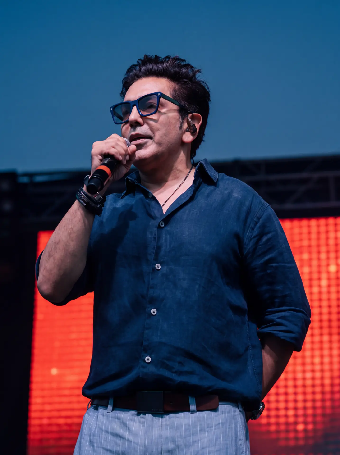Singer in sunglasses and a blue shirt performing in daylight