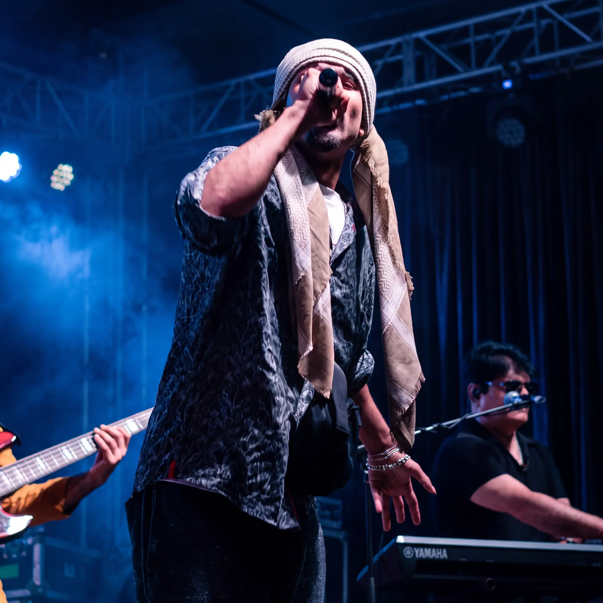Vocalist performing with band under blue stage lighting