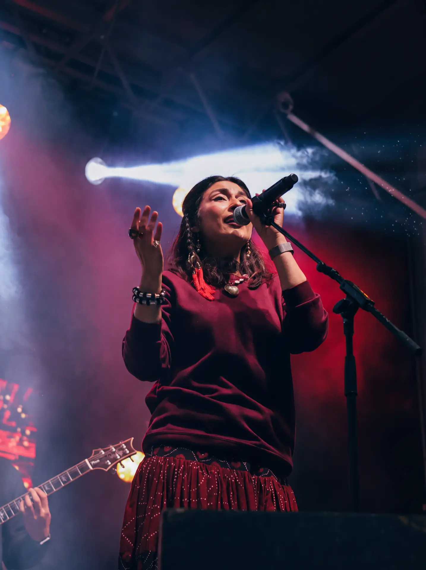Singer raising a hand mid-song beneath stage lights