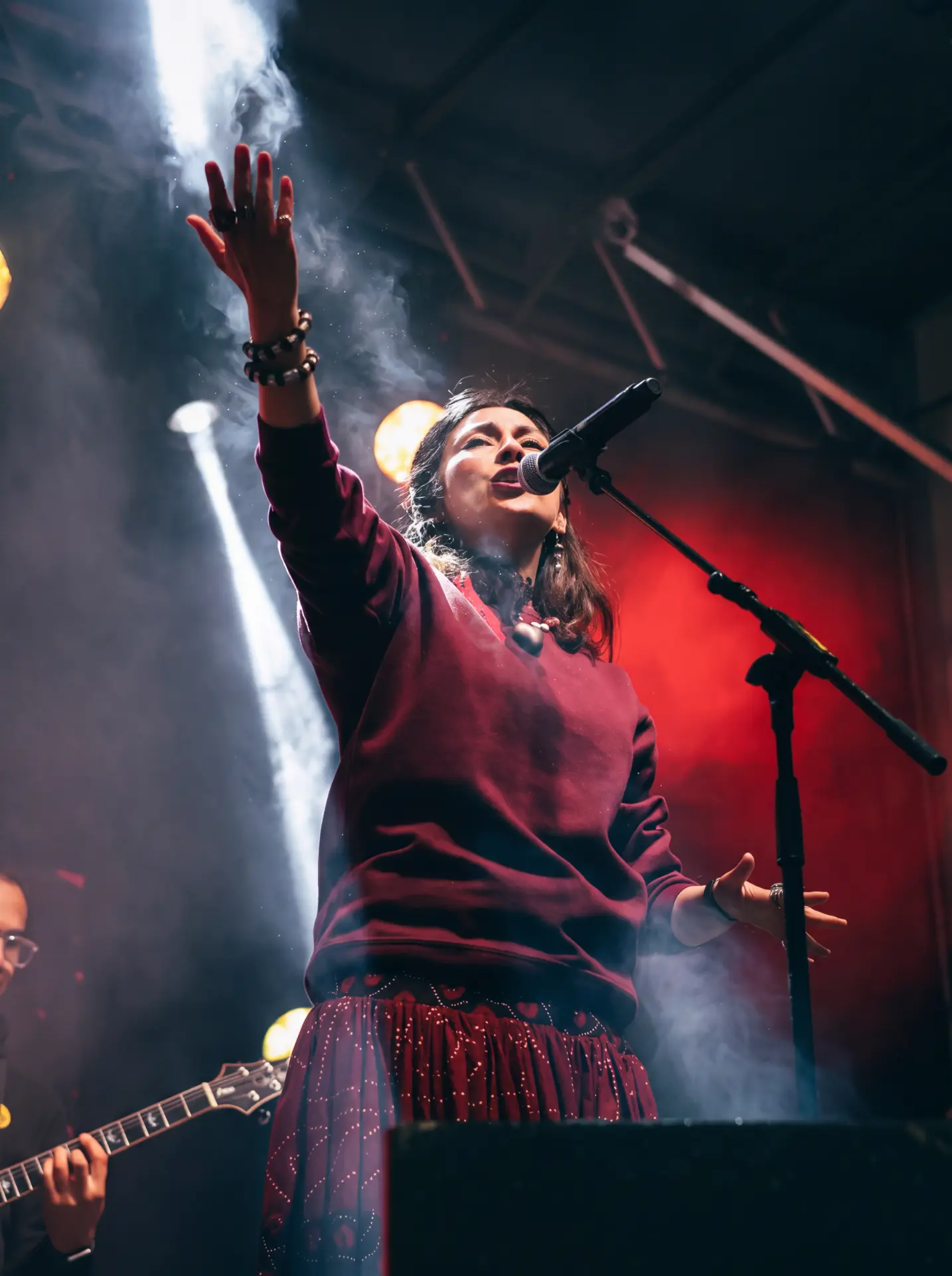 Singer with a raised hand amid smoke and spotlights