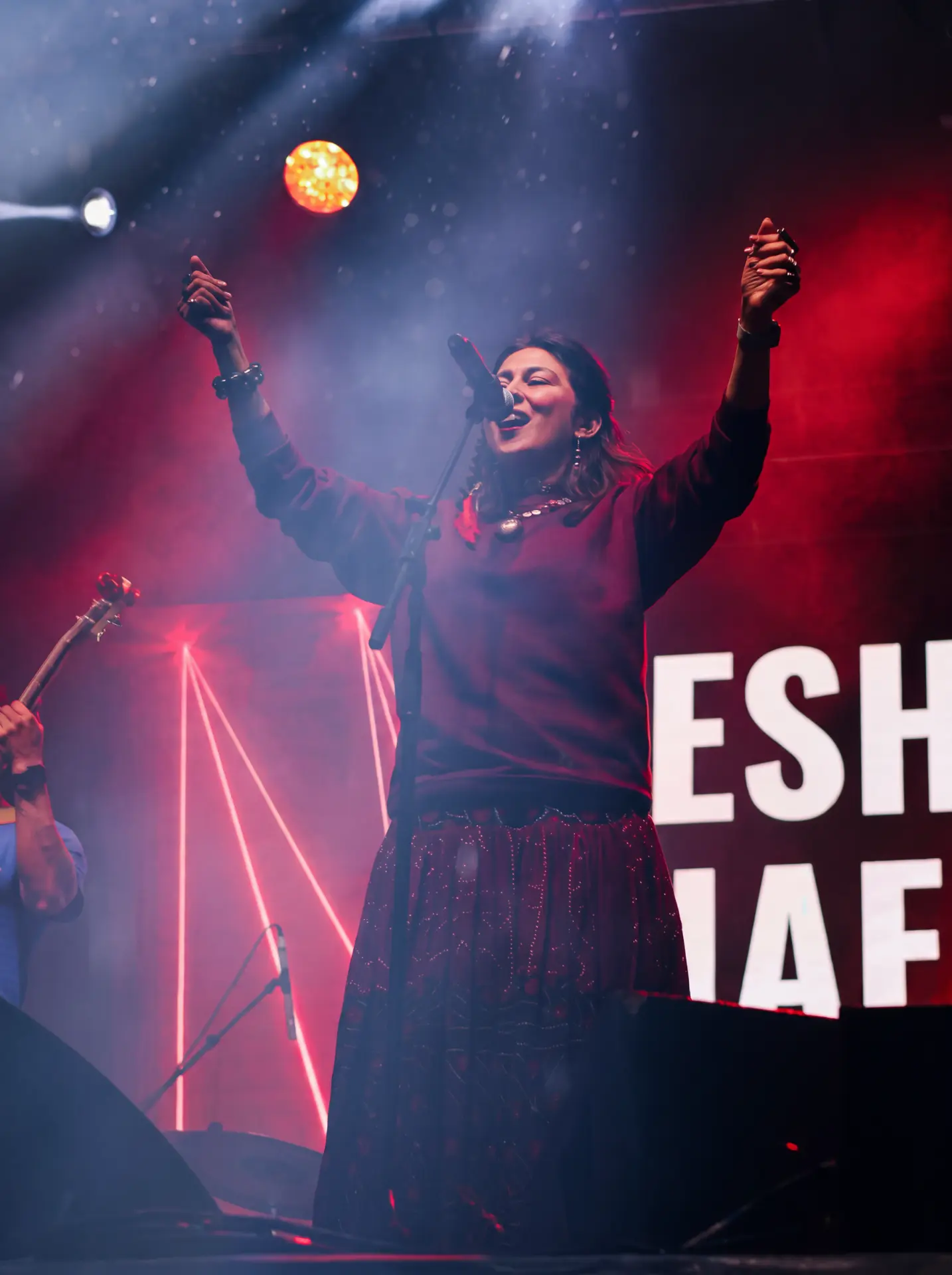 Singer with arms raised in front of the festival backdrop