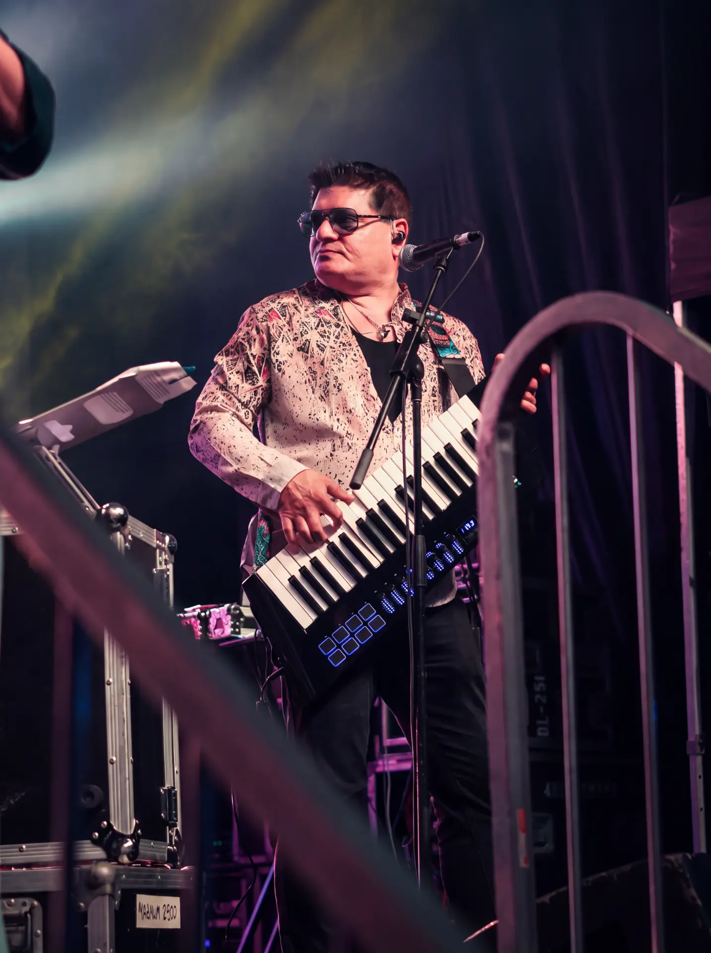 Keyboardist playing a keytar on stage under warm lighting
