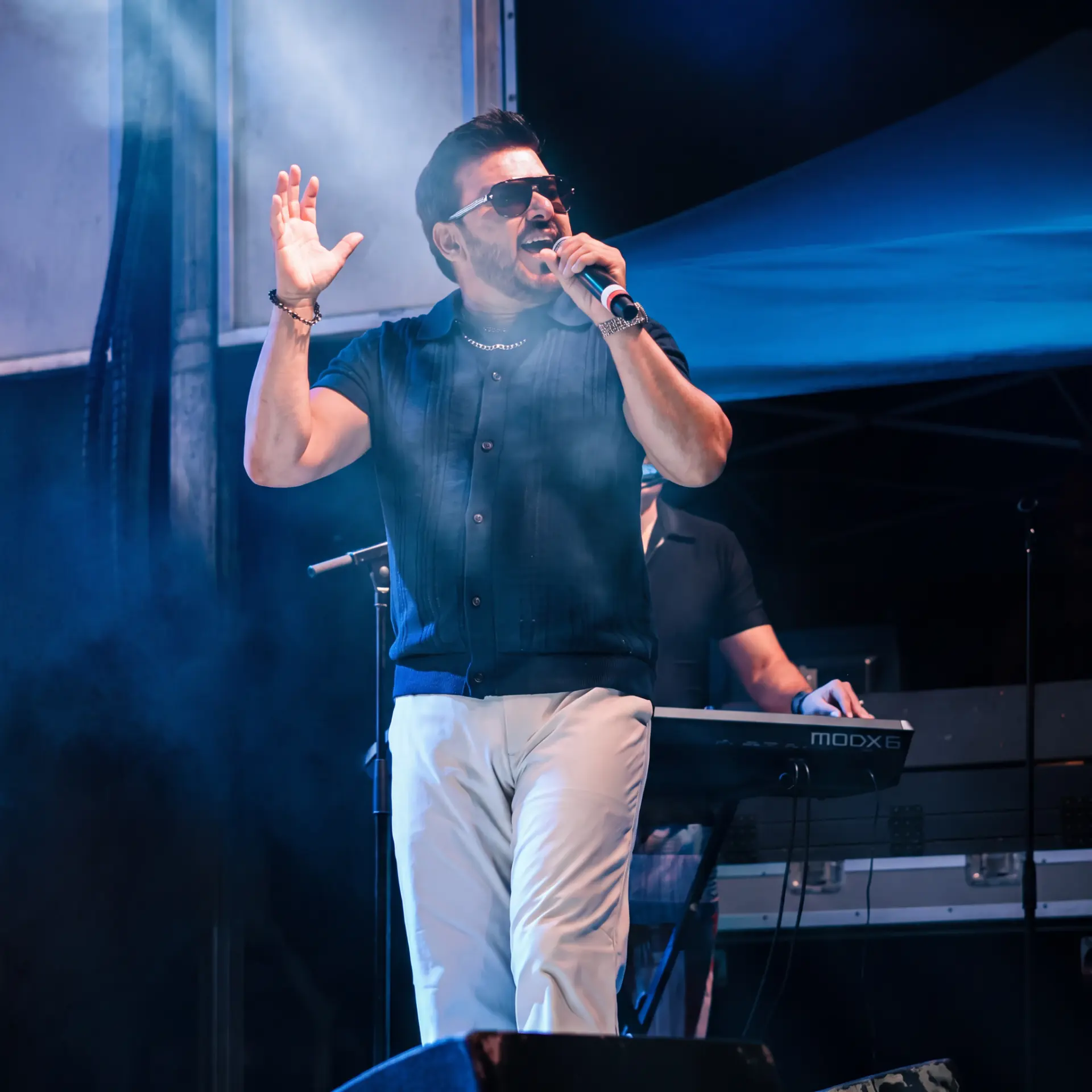 Singer wearing sunglasses performing in front of a keyboardist