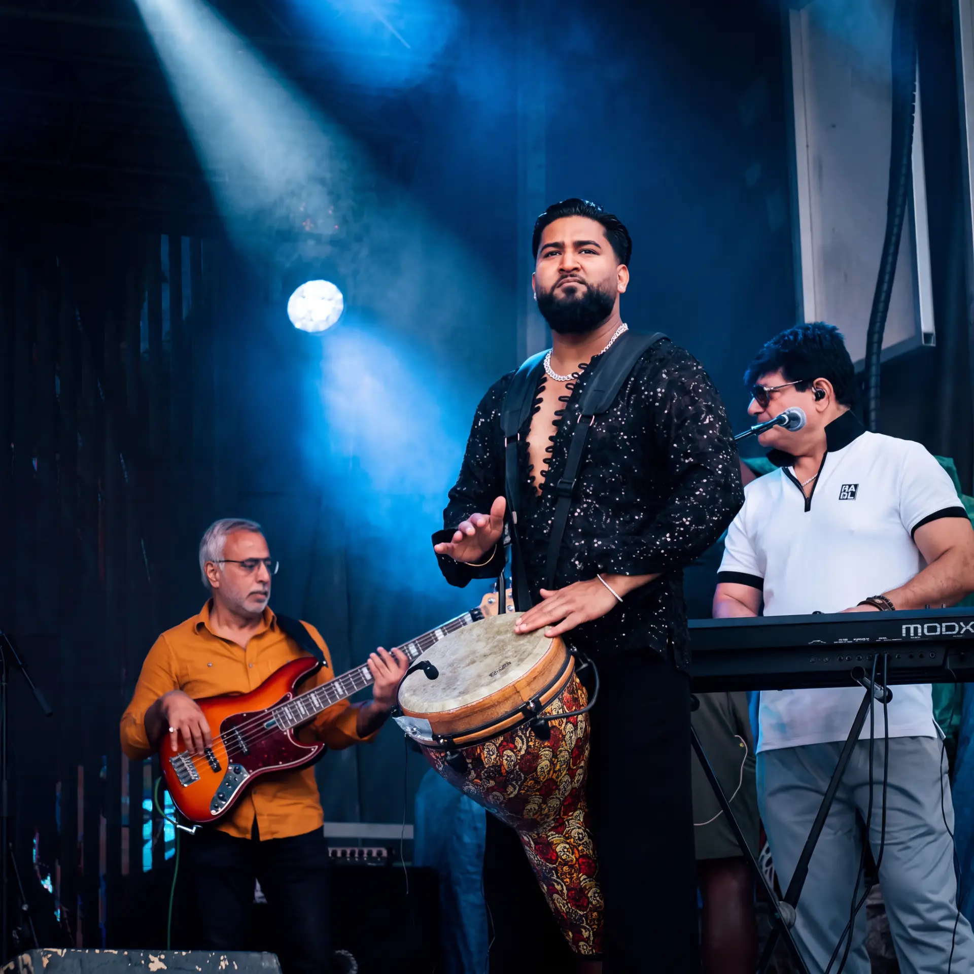 Band performing together under a blue spotlight